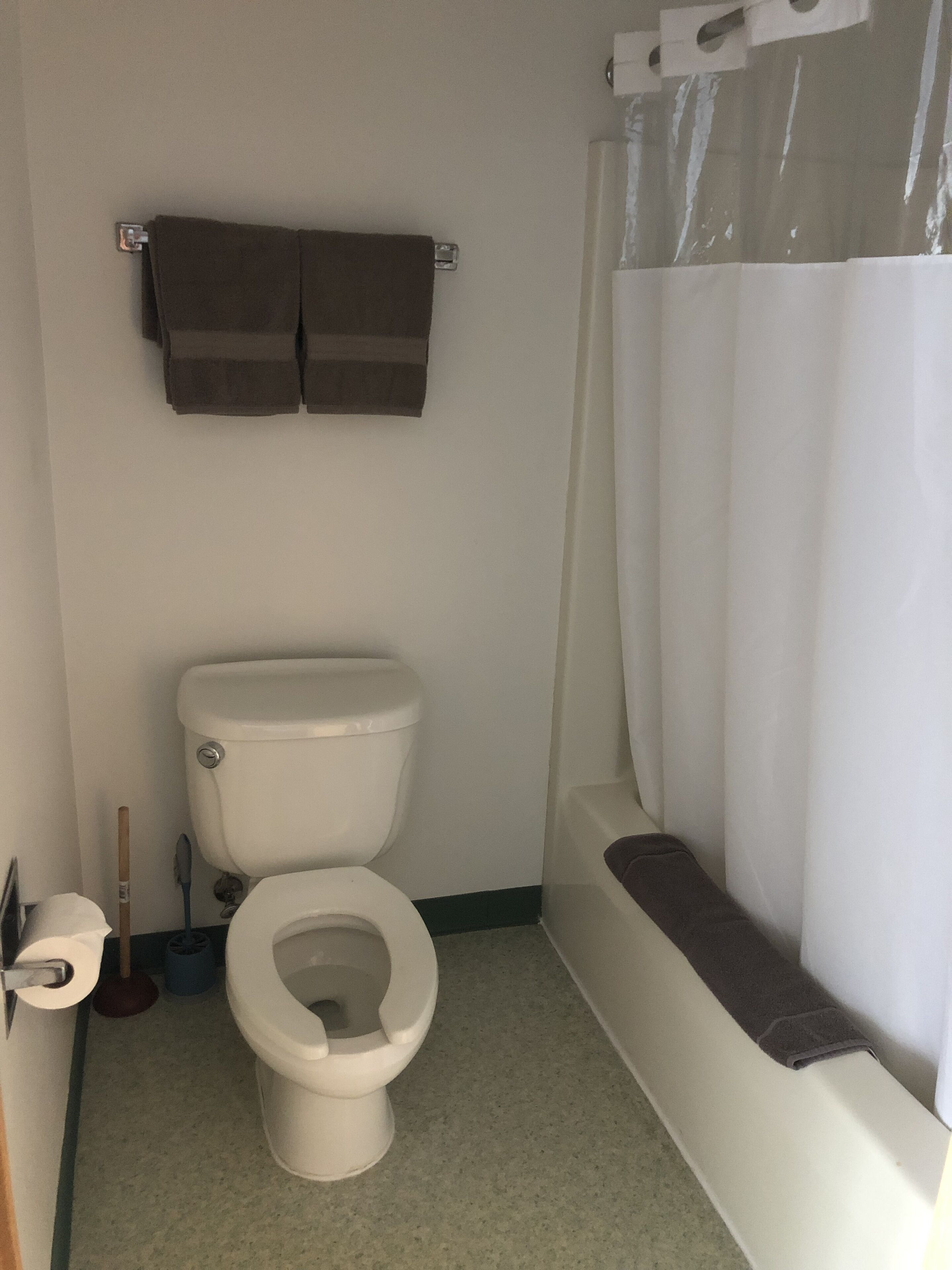 A bathroom with a toilet, a bathtub, and a shower curtain.