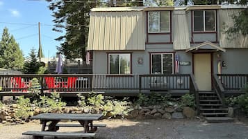 Step into a charming outdoor space with a welcoming entrance, picnic table, and beautifully landscaped surroundings.