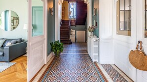 Un pasillo con baldosas de diseño, una escalera y una sala de estar con sofá y espejo.