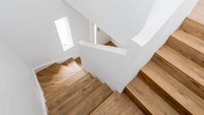 Un escalier en bois, avec des murs blancs et une petite fenêtre.