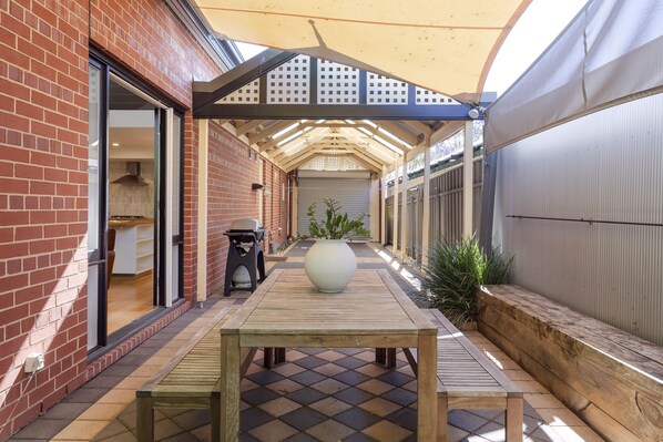 Relax in the shaded patio area with a wooden table and planter.