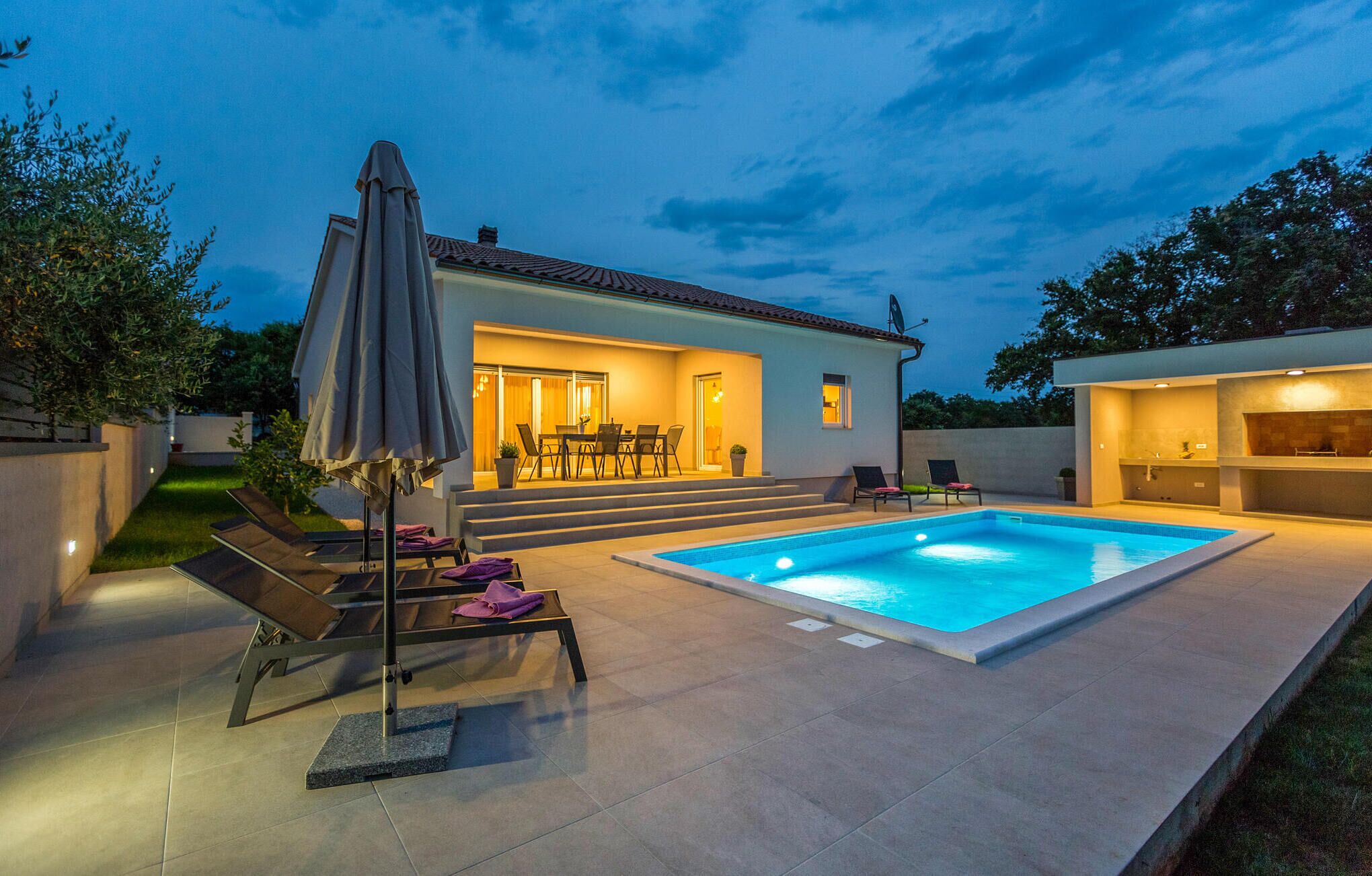 Una casa moderna con piscina, mobiliario exterior y zona de patio.