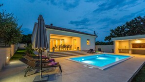 Une maison moderne dotée d’une piscine, d’un espace salon extérieur et d’un patio.