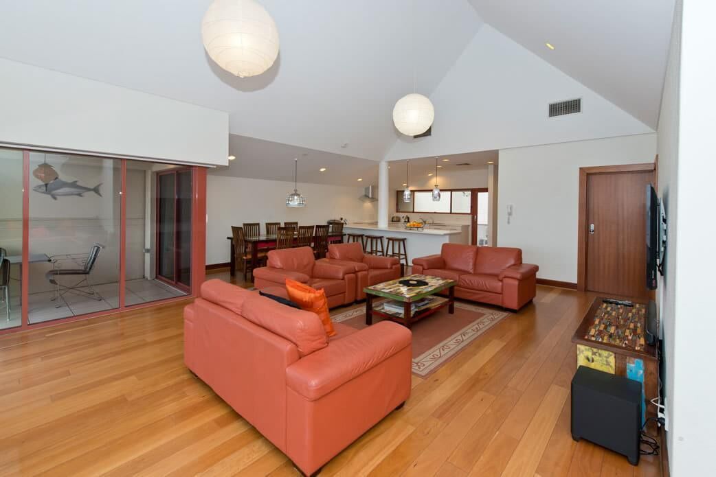 A spacious living room with a large sofa, a coffee table, and a dining area with chairs and a table.