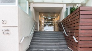 Una escalera conduce a un área de recepción con un letrero que indica 'Reception' y 'Puerta de seguridad contra incendios'.