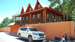 Een witte SUV geparkeerd voor een gebouw met een rood dak en een balkon.