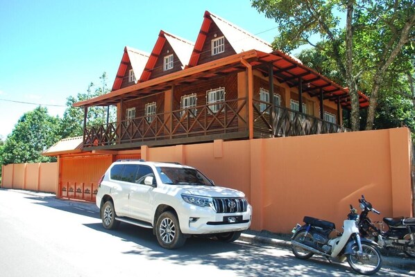 Un SUV blanco estacionado frente a un edificio con techo rojo y balcón.