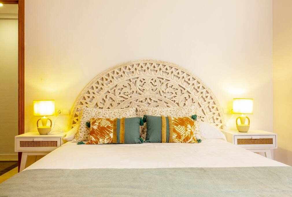 A bed with a decorative headboard, two bedside lamps, and a patterned pillow.