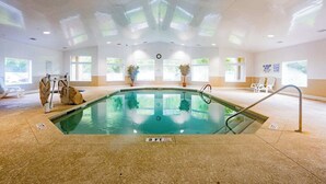 An indoor swimming pool with clear water, surrounded by a tiled floor and walls, with windows allowing natural light. - Coastal Villa by the Beach (Hilton Head Island)