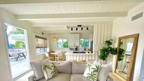 A living room with a sofa, a dining area, and a kitchen. - Encinitas Surf Shack w/ Private Rooftop Oasis (Encinitas)