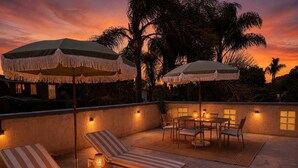 An outdoor patio with lounge chairs, a table, and umbrellas. - Encinitas Surf Shack w/ Private Rooftop Oasis (Encinitas)