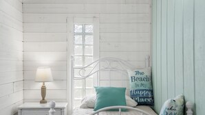 A white wooden bedroom with a single bed, a nightstand with a lamp, and a window with a view. - Emerald Coast Paradise Condo, Steps from PCB Beaches! (Panama City Beach)