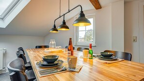 A dining area with a wooden table, black chairs, and pendant lighting. - Apartment 'Residenz Unter Den Linden Falke' with Wi-Fi (Mühlhausen)