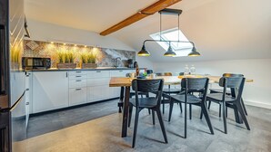 A modern kitchen with white cabinets, a wooden dining table, and black chairs. - Apartment 'Residenz Unter Den Linden Falke' with Wi-Fi (Mühlhausen)