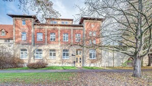 A historic building with multiple windows, a central entrance, and a surrounding grassy area. - Apartment 'Residenz Unter Den Linden Falke' with Wi-Fi (Mühlhausen)