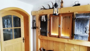Un interno in legno con una porta ad arco, una panca e uno scaffale a parete con diversi oggetti.