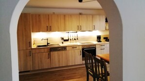 Una cucina con mobili in legno, lavastoviglie, lavello e macchina per il caffè.