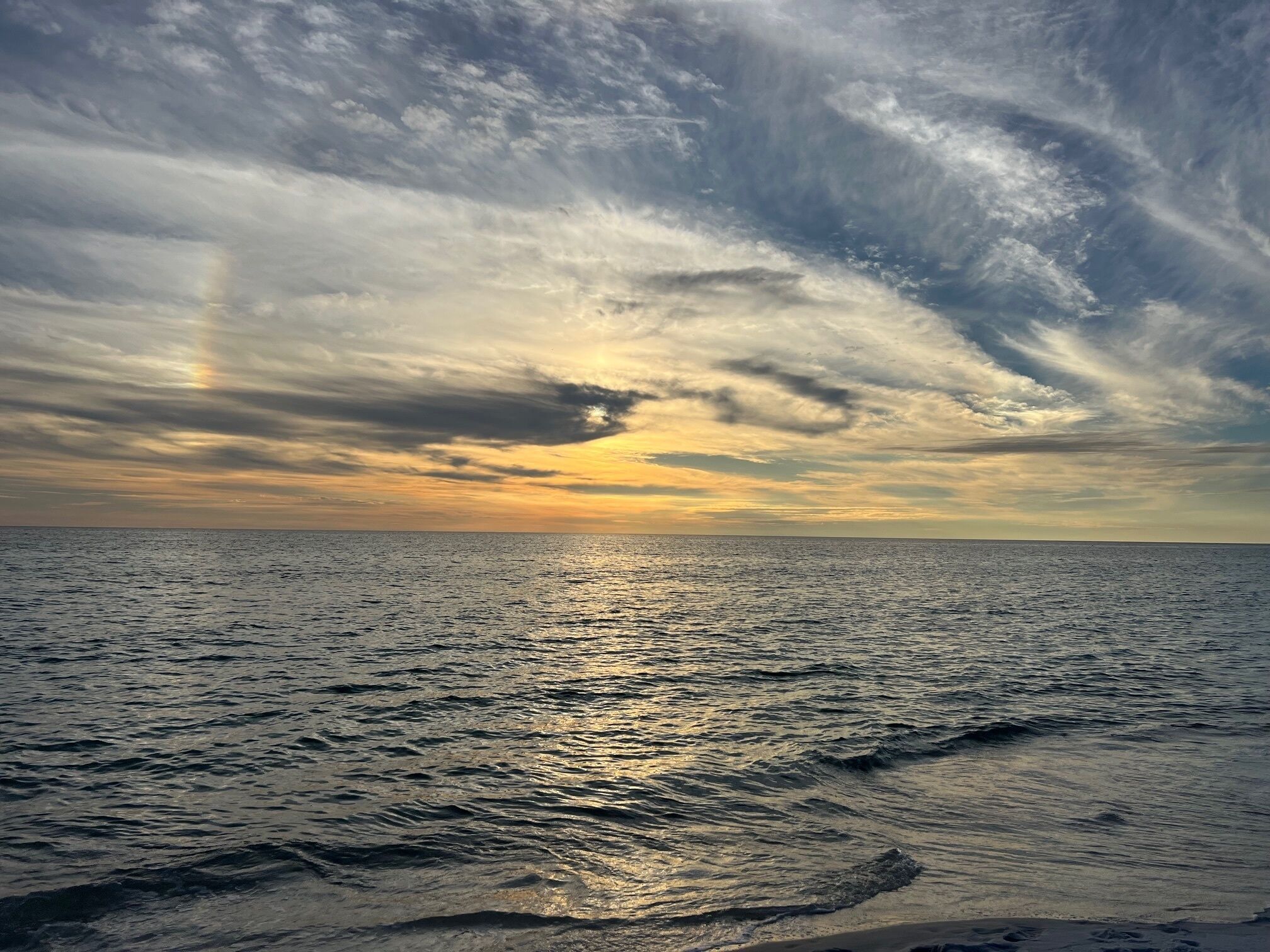 A beach with a view of the ocean and a cloudy sky.