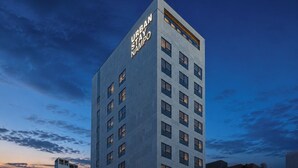 Un edificio moderno e slanciato con la scritta 'URBAN STAY', caratterizzato da una griglia di finestre e un tetto piatto.