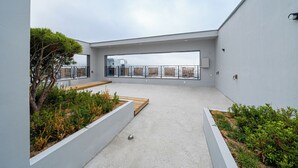 Una terrazza sul tetto con pavimento in cemento, pareti bianche e una panca in legno.