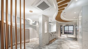 Un interno moderno con pavimento in marmo, pannelli in legno e un soffitto dalla forma curva.