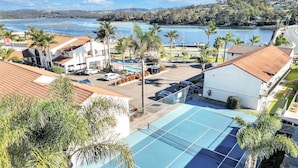 A coastal hotel with a pool, palm trees, and a view of the sea.