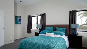 Un dormitorio con una cama grande, dos mesitas de noche, una ventana con cortinas y un cuadro en la pared.