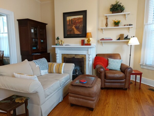 A living room with a fireplace, a sofa, a chair, and a coffee table. - Urban Cottages of Little Rock (Little Rock)