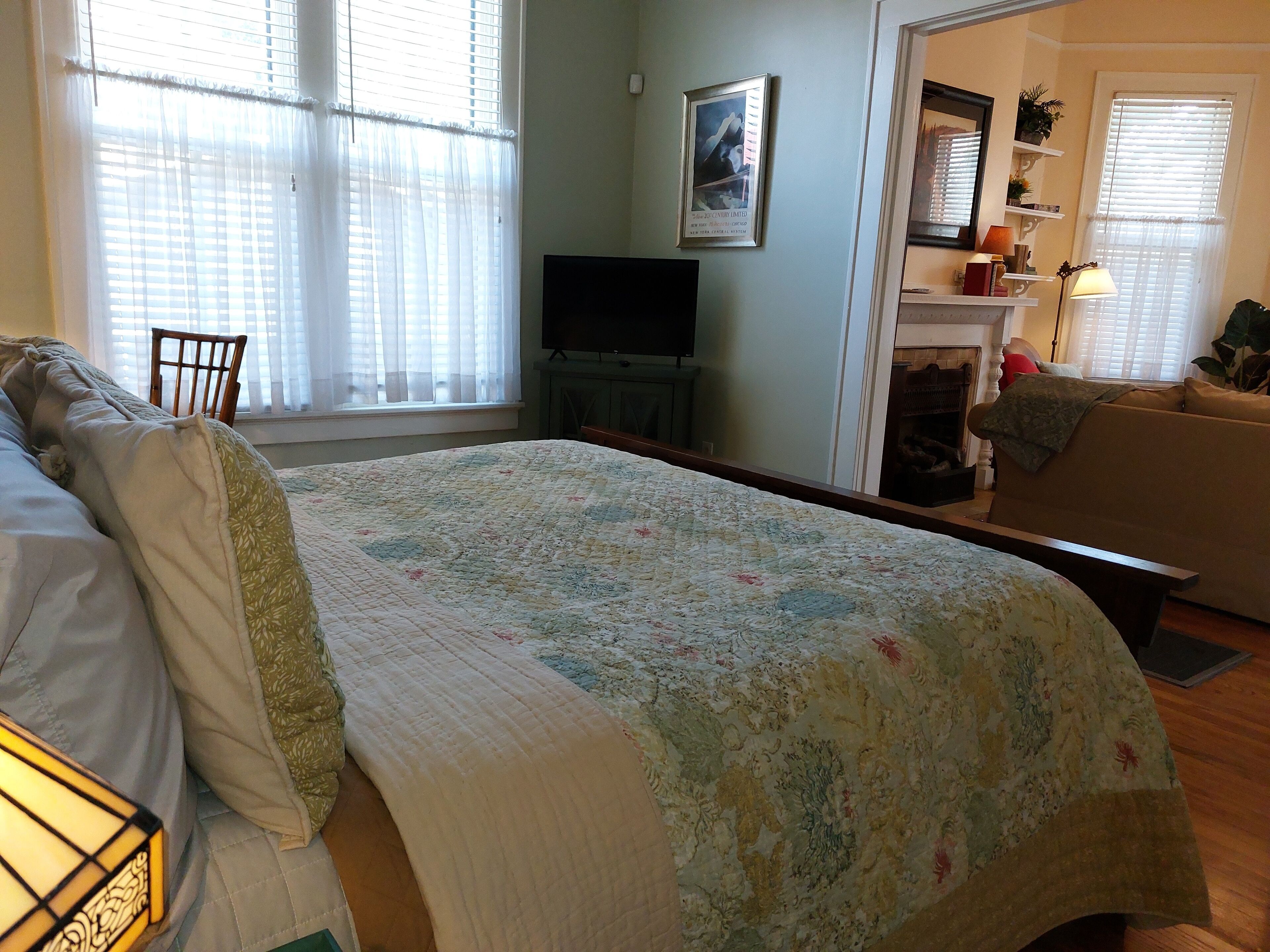 A bedroom with a bed, a television, a sofa, and a fireplace.