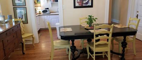 A dining area with a black table, yellow chairs, and a painting above.