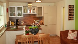 A compact kitchen with wooden cabinets, a dining table, and a sofa.