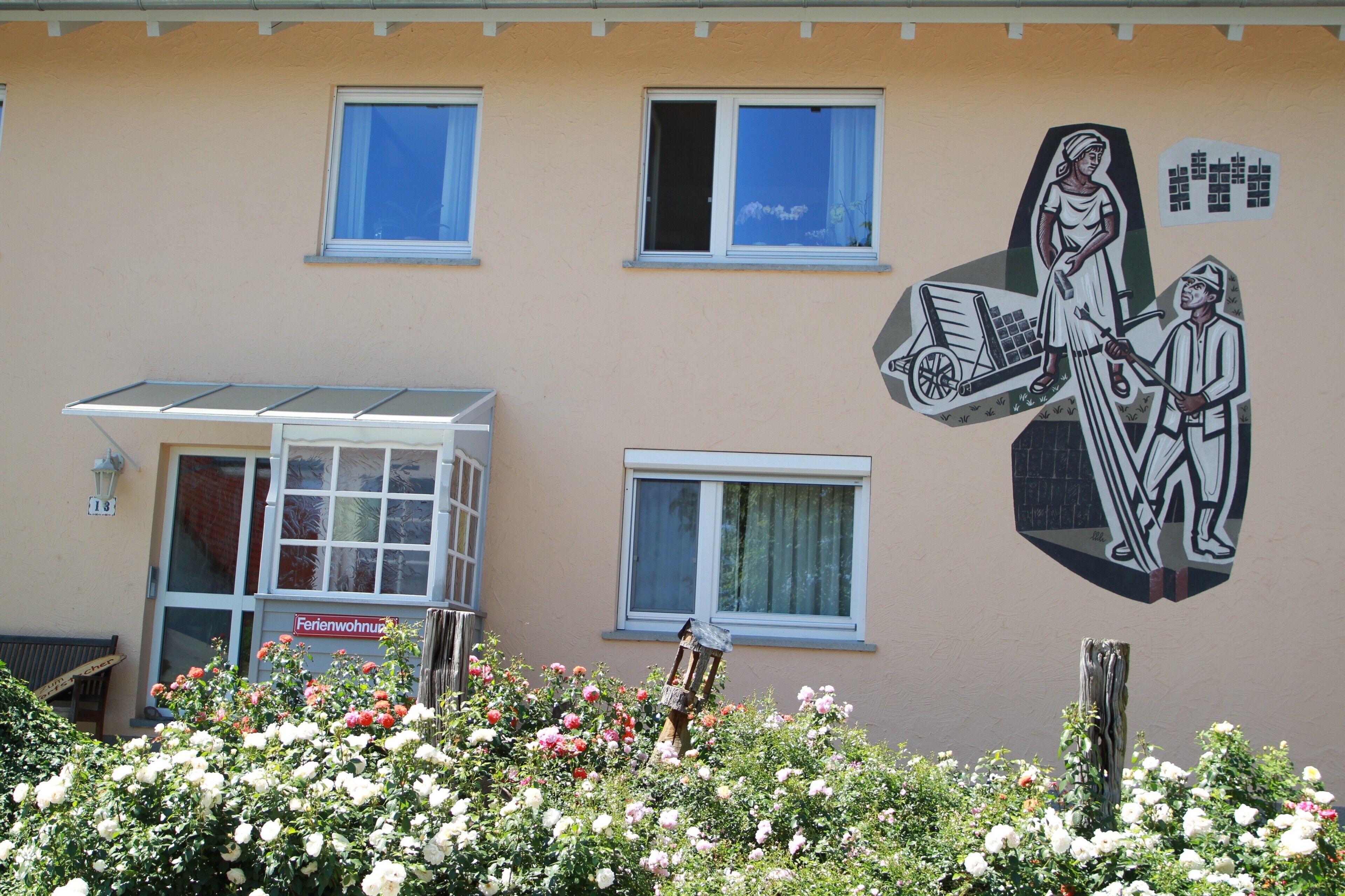 Un edificio con un mural, ventanas, una puerta y un cartel que dice 'Ferienwohnung'.