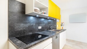 Eine moderne Küche mit schwarzem Arbeitsplatz, weißen Schränken und einem gelben Oberschrank.