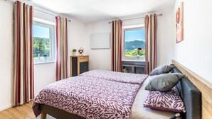 Ein Schlafzimmer mit Bett, Vorhängen, Schreibtisch, Stuhl und einem Fenster mit Aussicht.