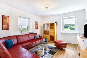 Una sala moderna con un sofá de cuero rojo, una mesa de centro de vidrio y un mueble de madera.