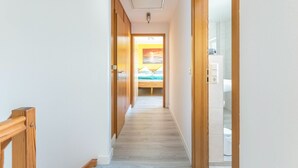 En hall som leder till ett sovrum med en säng, ett badrum med en toalett och en dörrkarm i trä.