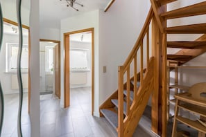 A staircase with wooden railings and a view of a room with a white door and a window. - Vacation Home "Niebüllhus" with Private Terrace & Wi-Fi (Niebüll)