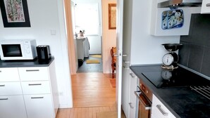 Une cuisine moderne avec des meubles blancs, un four à micro-ondes, une bouilloire et une balance.