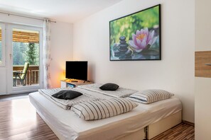 A bedroom with a bed, pillows, a TV, and a window with a view of trees.