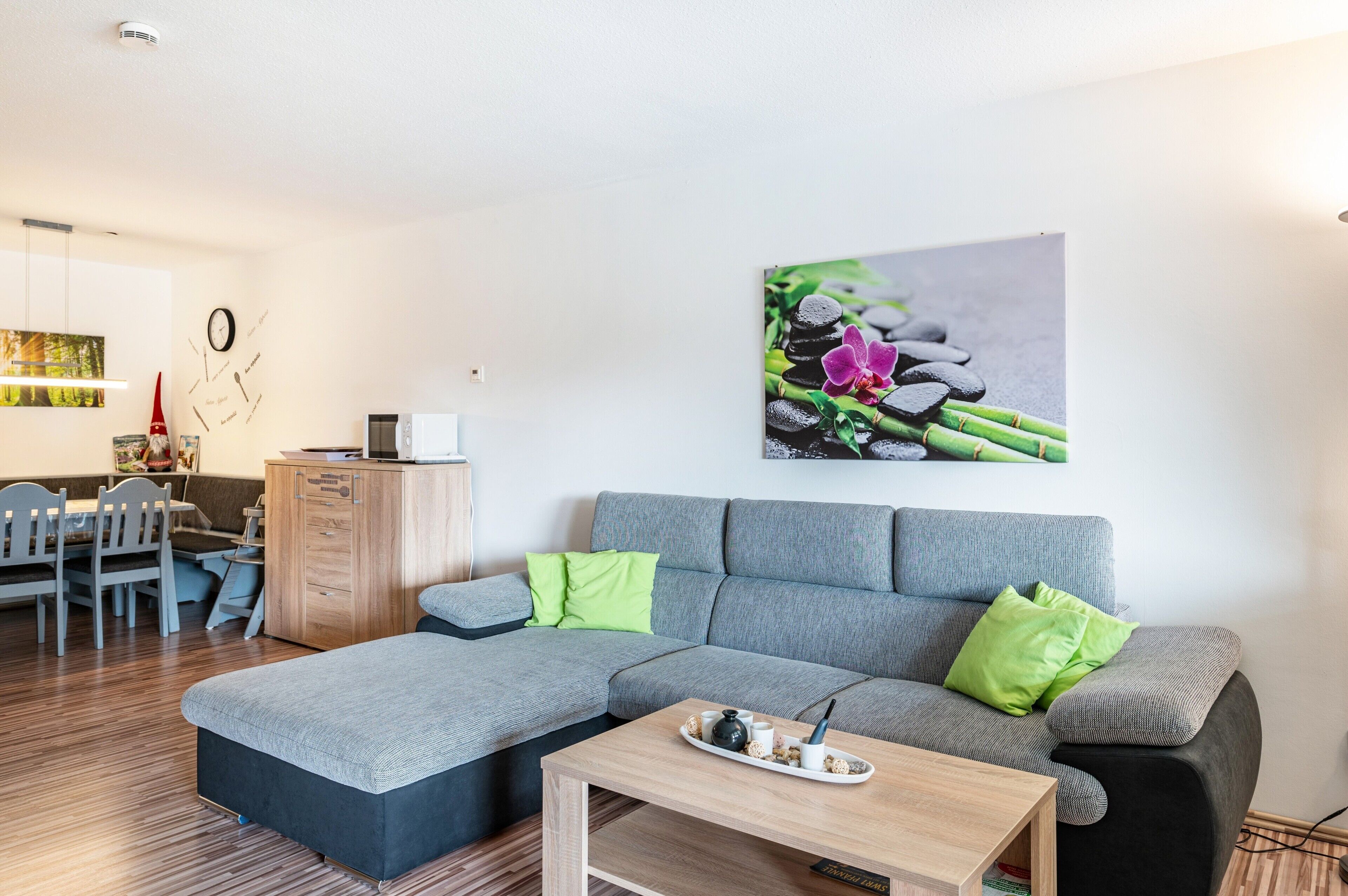 A modern living room with a sectional sofa, a dining area, and a kitchen in the background.