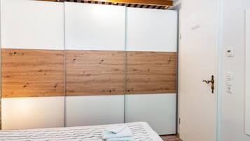 A bedroom with a bed, a wooden panel wall, a white door, and a light switch.