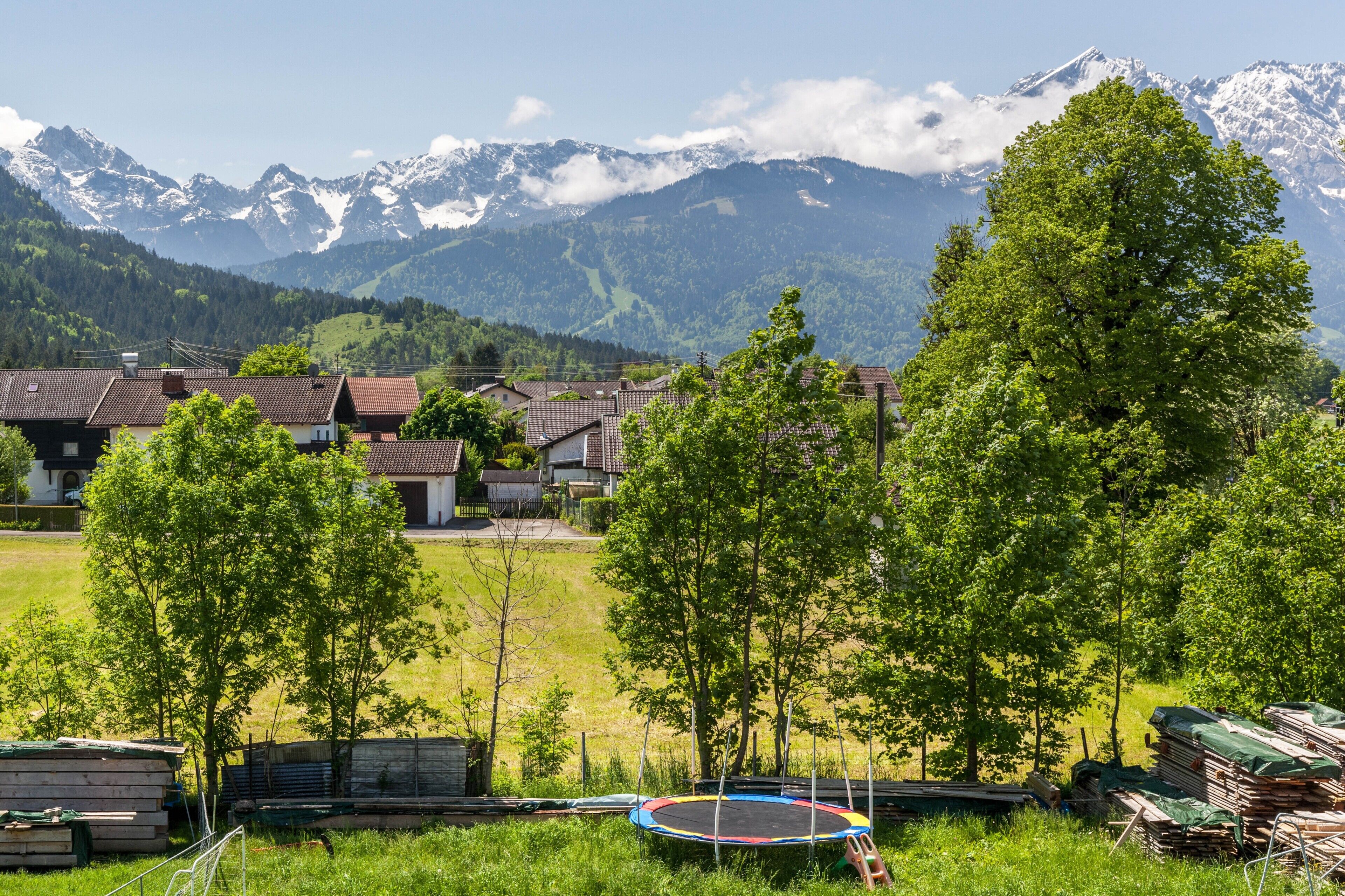A residential area with houses, a trampoline, and a mountain backdrop.