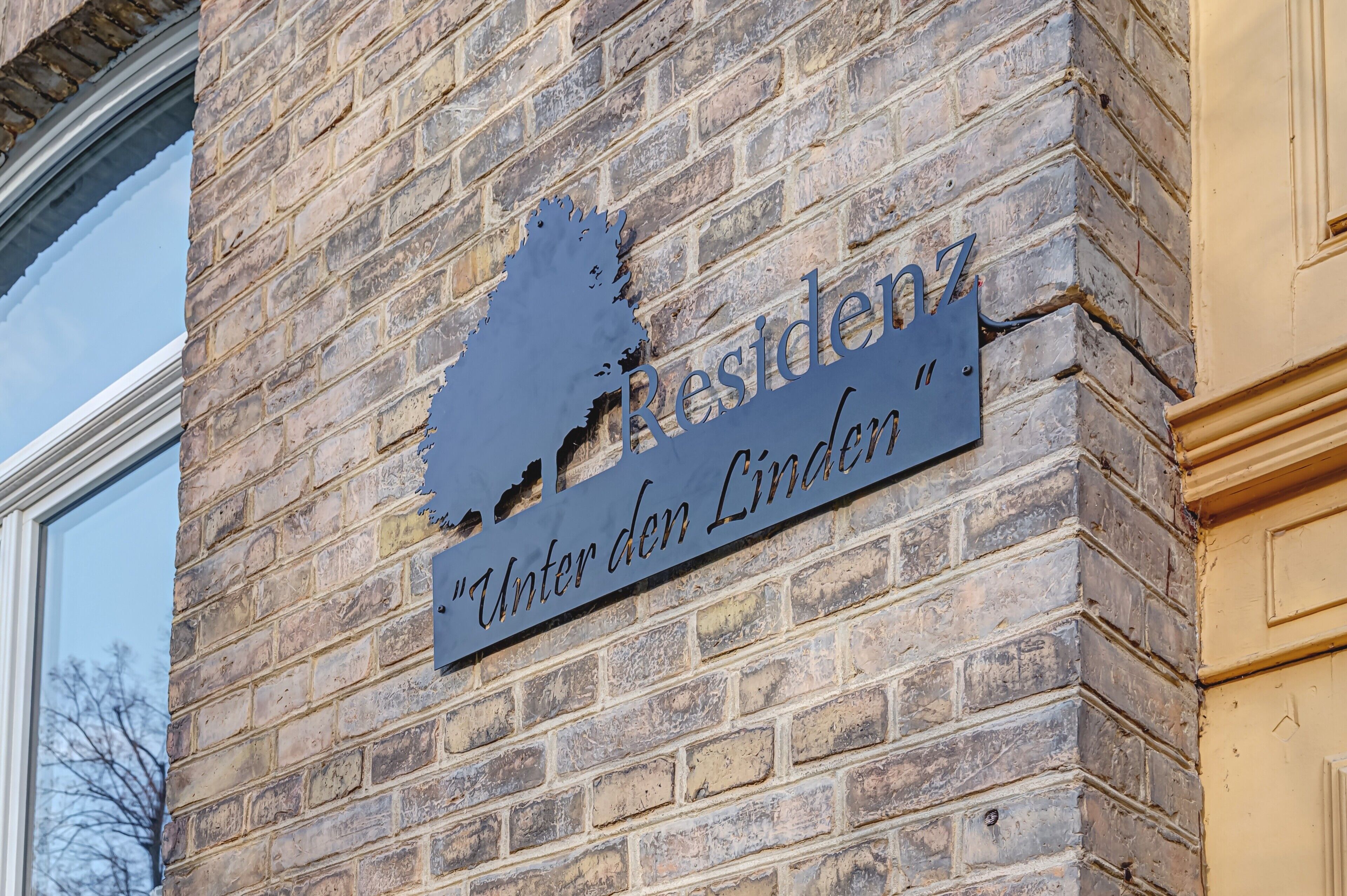 A brick building with a metal sign that reads 'Residenz Unter den Linden.'