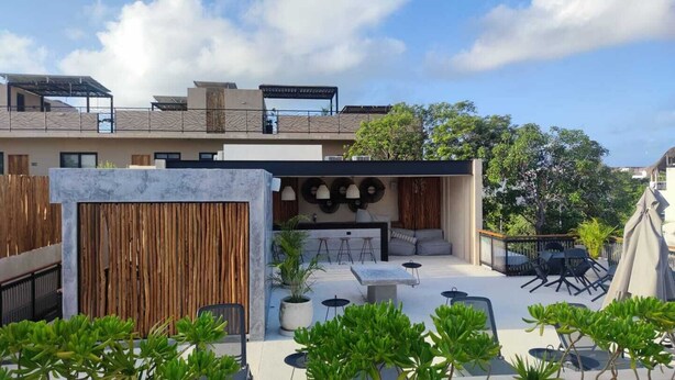 Una terraza en la azotea con mobiliario exterior, una valla de madera y vistas del horizonte de la ciudad.