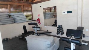 Un gimnasio con equipo de ejercicio, una banca y un espejo.
