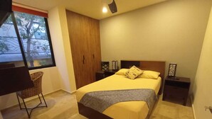 Un dormitorio con cama, mesita de noche, silla, armario y ventana.