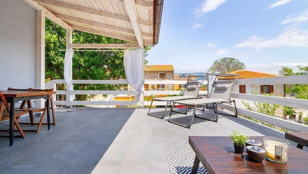 A balcony with a wooden pergola, a table with a candle, and a chair. - Apartment Kleine Perle Am Meer (Silo - island Krk)