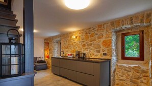 A kitchen with a stone wall, a window, and a built-in stove. - Apartment Kleine Perle Am Meer (Silo - island Krk)