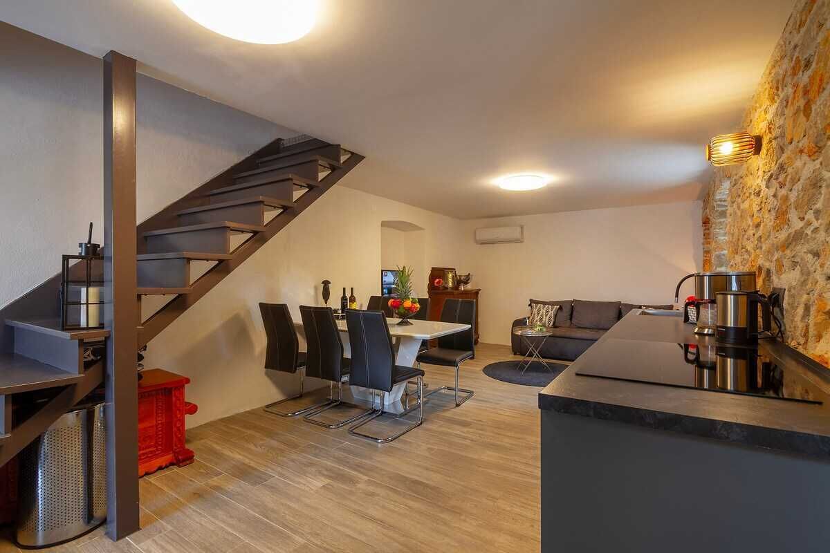A modern kitchen with a staircase, dining area, and a coffee station.