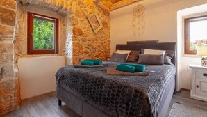 A stone-walled bedroom with a bed, a window, and a nightstand. - Apartment Kleine Perle Am Meer (Silo - island Krk)